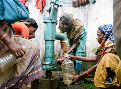 Woman filling up a bottle of water in a village