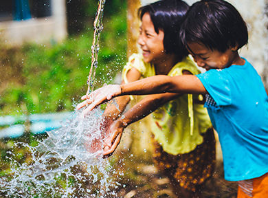 Two children in the village having fun playing with water