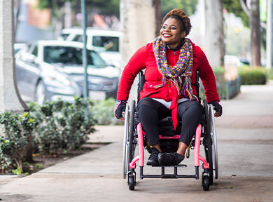Woman in her wheelchair going down the road enjoying the fresh air