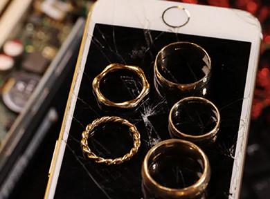Five rings sitting on top of a cracked iPhone